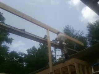 Carpenter setting a ridge beam over a new addition frame — Ice Dam Removal by Roofing Brothers in Towaco