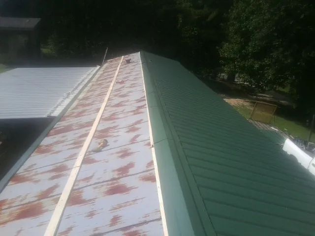 Old rusted panels beside newly installed green metal roofing — Wind Damage Roof Repair by Roofing Brothers in Towaco