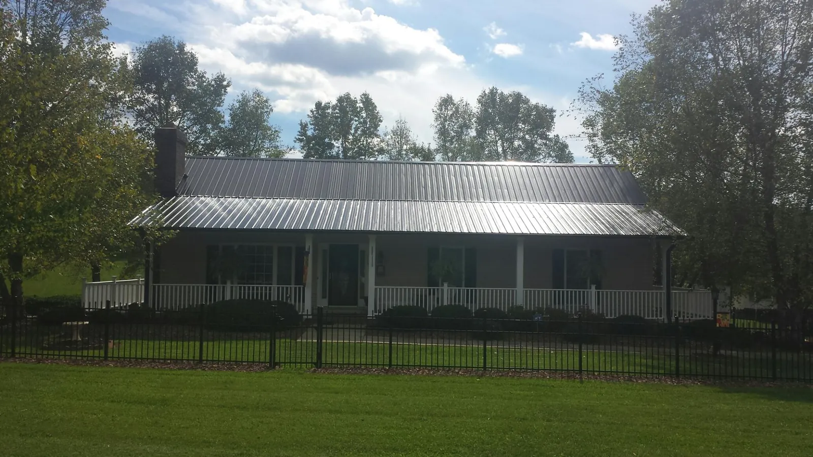 Gray metal roof on a brick ranch with a full width front porch — Gutter Guard Installation work by our crew in Towaco