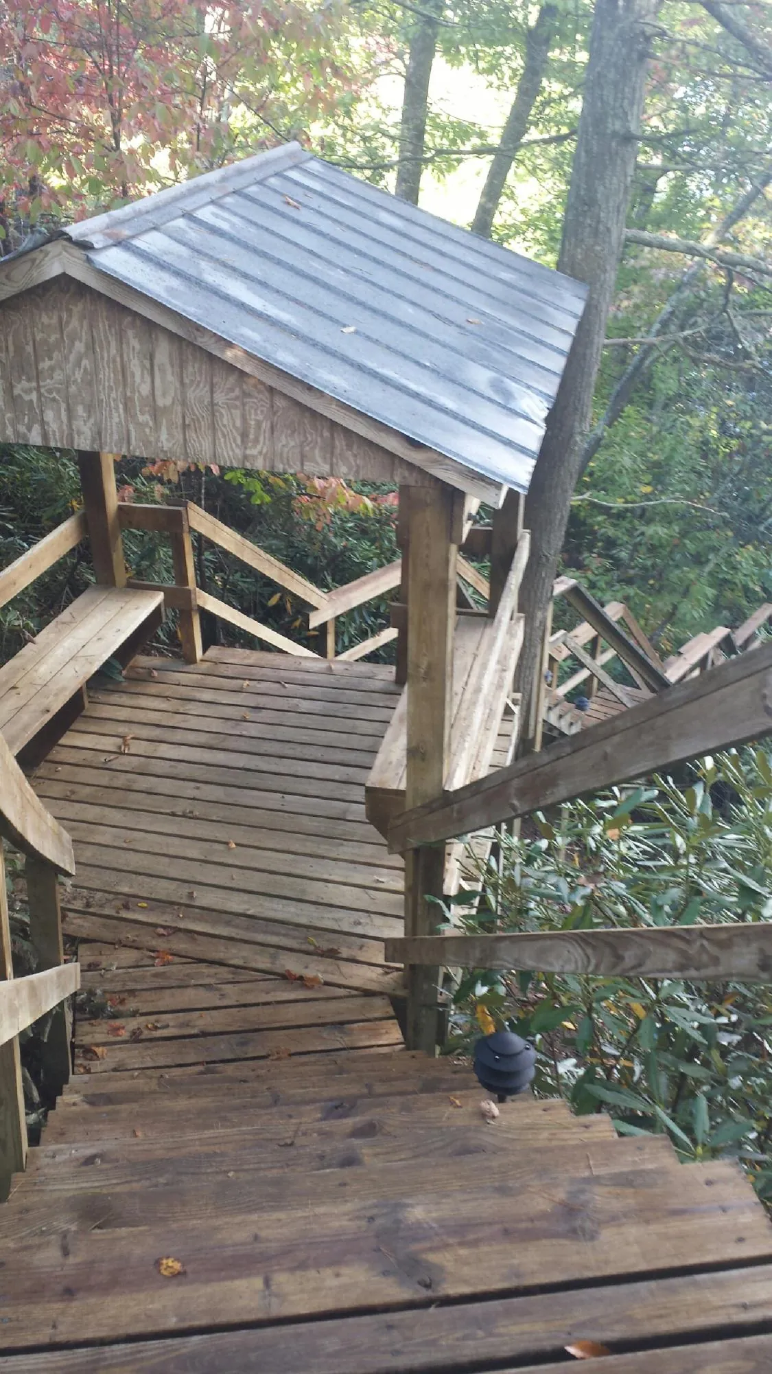 Metal roofed shelter over wooden steps on a wooded walkway — Skylight Repair & Installation work by our crew in Towaco