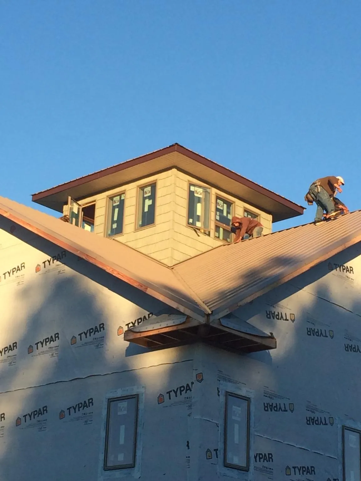 Roofers working around a rooftop cupola on a new metal roof at sunset — Roof Waterproofing in Towaco by Roofing Brothers